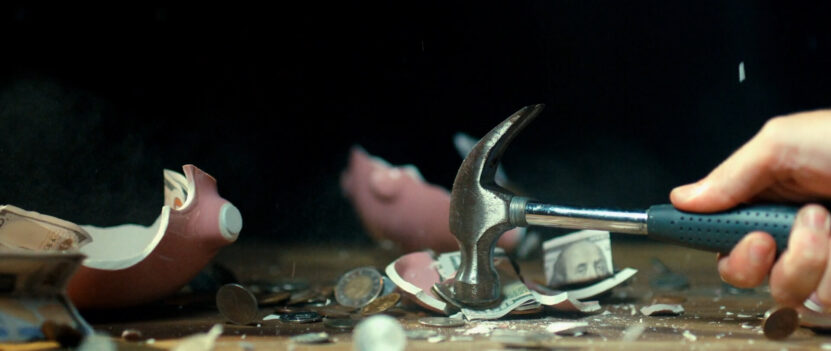 Smashing piggybank with hammer